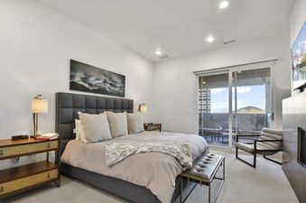 A luxurious king bedroom at Apex 1501 features a large bed, modern fireplace, and a sliding glass door leading to a private balcony with mountain views.