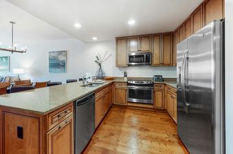 A modern kitchen in BlueSky Breckenridge 504 with wooden cabinets, light-colored granite countertops, and stainless steel appliances, featuring a spacious island with a sink and seating.