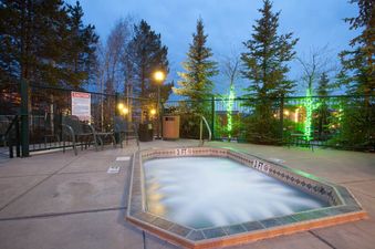 An inviting outdoor hot tub at Kutuk 212 surrounded by pine trees at dusk.