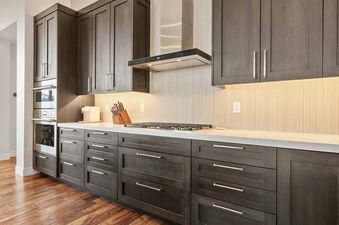Modern kitchen with dark wood cabinets, white countertops, and built-in appliances in the SkyRidge 1307.