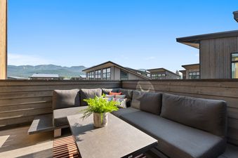 The private outdoor terrace at Quarry B10 with a sectional sofa and mountain views under a clear blue sky.