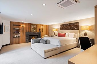 A luxurious bedroom at The Charter L022 with a large bed, chaise lounge, fireplace, and ambient lighting.