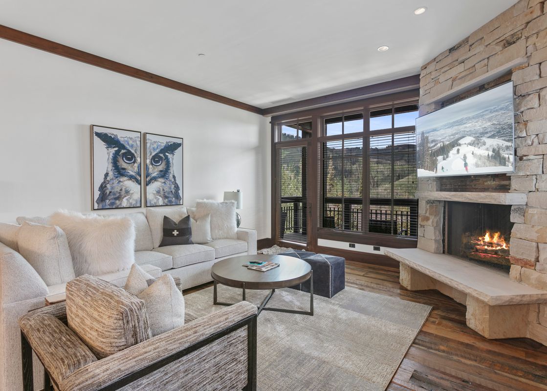Cozy living room in Arrowleaf 209 with a stone fireplace, white sectional, and large scenic windows.