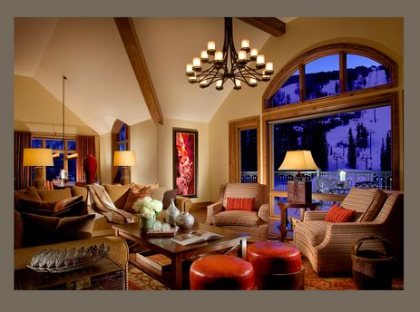 A cozy, luxuriously furnished living room in the Arrabelle 1 Bedroom with views of a snowy ski resort at twilight.