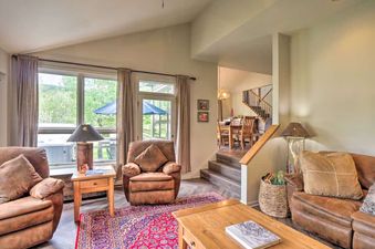 Cozy living room inside the Copper Mountain Home with Hot Tub, featuring leather armchairs, a wooden coffee table, a colorful rug, and steps leading to the dining area.