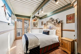 A cozy bedroom in Black Forest Dreams featuring an ornate carved wooden headboard and a balcony door.