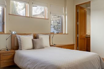 A modern and cozy bedroom at Skyline Estate with windows overlooking a snowy exterior.