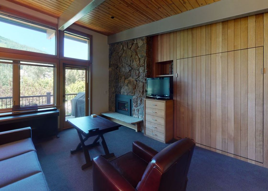 Manor Vail 370 living area with a fireplace, TV, and a view of the mountains.