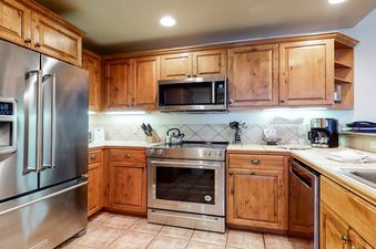 EagleRidge Lodge 300 kitchen with stainless steel appliances, wood cabinets, and a tiled floor.
