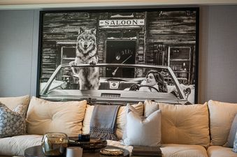 The Clubhouse living room features a couch with pillows and a throw blanket, in front of a large framed black and white photograph.