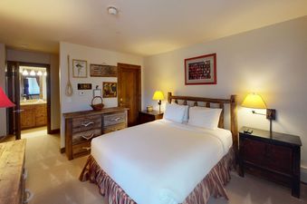 The bedroom at Manor Vail 274 features a king-size bed, nightstands, and a wooden dresser.