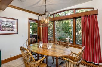 A close-up view of the Plaze Lodge 3 Bedroom Gold Unit 2's dining area with a wooden table, chairs, and a window.
