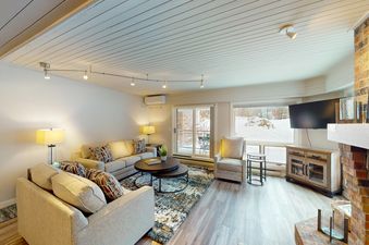 The living area of Dulany 105, featuring cozy seating and a fireplace, with a snowy exterior visible through the windows.