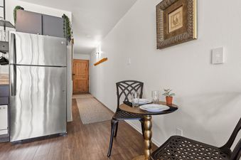 A dining table set for two with a refrigerator and hallway leading to a wooden door in Snowcrest 205.