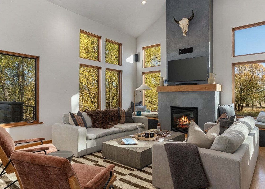 Modern living room at Alpenglow Jackson Hole with large windows and a fireplace.