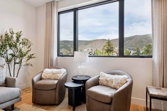 A cozy reading nook in Frontgate 226 with two leather armchairs, black side tables, a lamp, and a large window offering a view of hills.