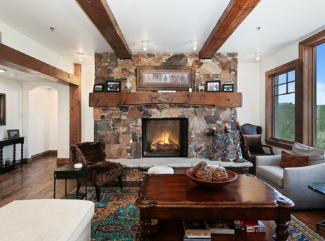 A cozy living room in Grand Lodge Three Bedroom Deluxe 308 with a fireplace and a view of the mountains.