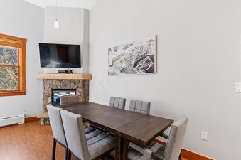 Dining area in Red Hawk Townhome 2349 with a table and chairs, adjacent to a stone fireplace.