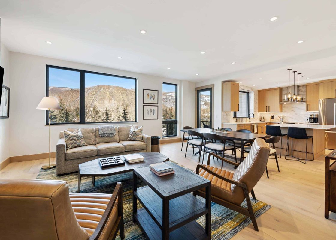 A living room in One Riverfront Condo 203 featuring a large couch with a mountain view from the window and a wooden coffee table with an area rug.