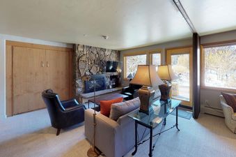 The living area in Manor Vail 166 Studio features a fireplace, comfortable furniture, and large windows with scenic views.