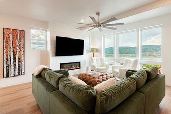 Modern living room at Deer Valley East Above and Beyond with a green sectional, fireplace, and scenic window views.