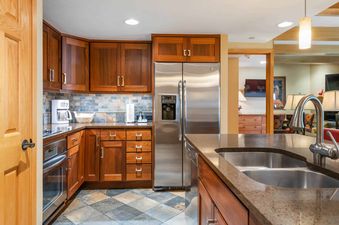 A modern kitchen with stainless steel appliances and dark wood cabinets, featuring a double sink and granite countertops.