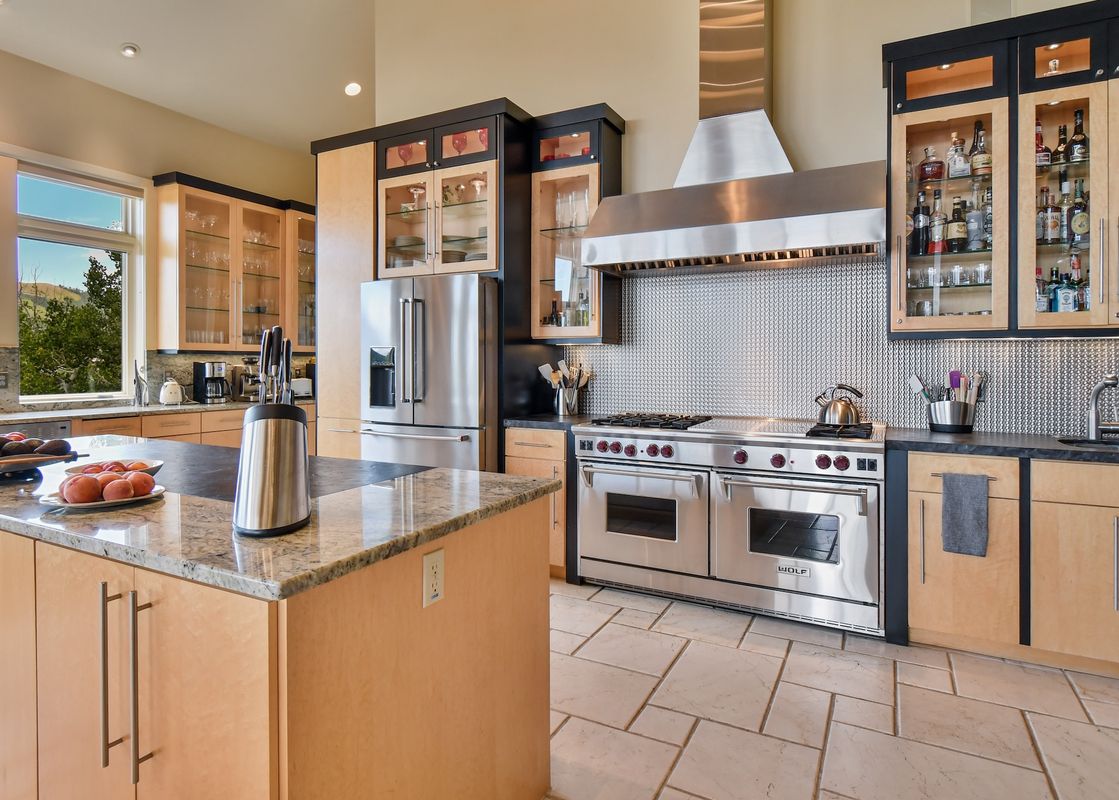 The kitchen at Sky Villa features stainless steel appliances, granite countertops, and light wood cabinetry, with a large window offering an exterior view.