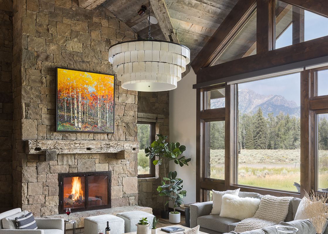 The Northern Exposure's rustic yet elegant living room with a stone fireplace, vaulted wooden ceilings, and expansive windows showcasing a mountain view.