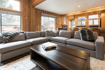 A living room with a sectional sofa, a coffee table, a rug, and a view of the outdoors.