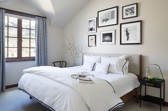 The serene bedroom at Four Pines 05, featuring a plush bed, framed artwork, and a window with a mountain view, creating a tranquil and inviting atmosphere.