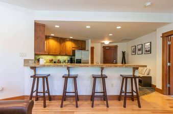 Kitchen with island bar with bar stools, a refrigerator and cabinets