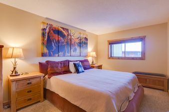 A bedroom with a king size bed, bedside table, and artwork above the headboard.