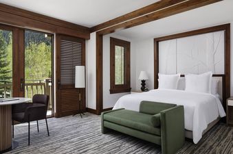 A luxurious bedroom at the Four Seasons Mountain Side Room featuring a king-size bed, elegant furnishings, and a balcony with a scenic mountain view.