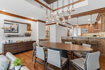 Dining area of Alpine at the Ritz Carlton with an oval table, modern lighting, and a kitchen background.