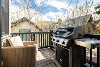 Balcony at Park City Woodside Escape with a wicker armchair and a Weber BBQ grill.