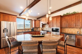 Fully equipped kitchen with wooden cabinets, granite island, and barstool seating in Deer Valley East Basecamp.