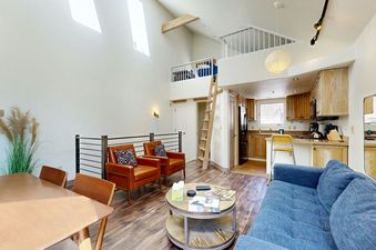 A cozy living room with a loft, leather chairs, and a large blue couch, perfect for relaxing after a day on the slopes.
