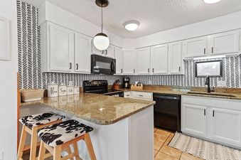 A modern kitchen with white cabinets and a granite countertop.