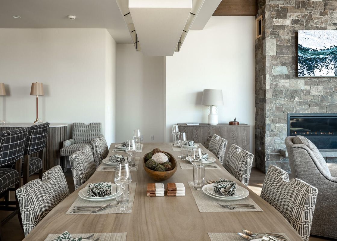 A dining room table is set for dinner with place settings, silverware, and glasses.