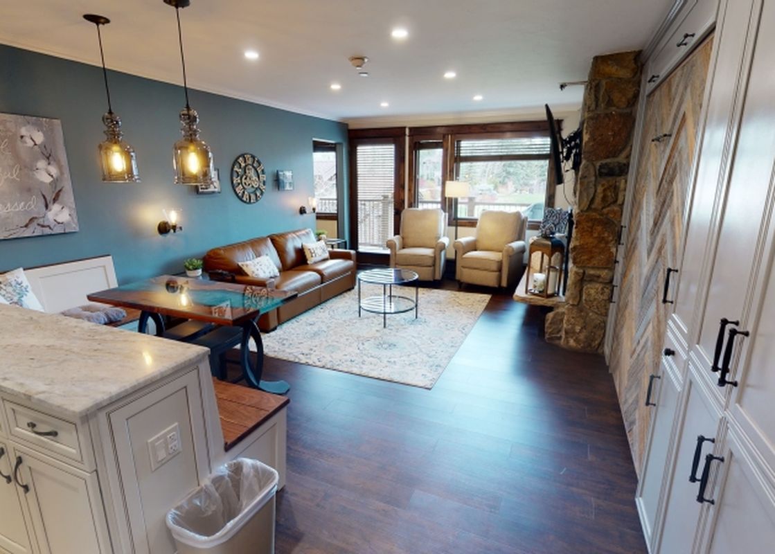 A living room with a fireplace and a large window overlooking a mountain view.