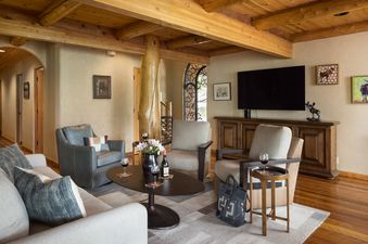 A cozy living room in Home on the Range with wood beams, comfortable seating, a flat-screen TV, and decorative artwork, featuring a natural and rustic design.