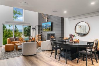 Modern open-plan living and dining area inside the Solstice Suite with large windows looking out on lush summer greenery.