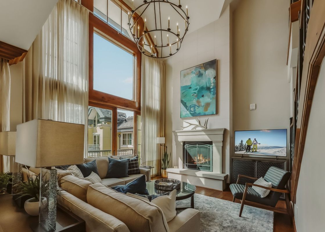A luxurious living room in Eagles Nest at the Ritz-Carlton features a stone fireplace, plush seating, and large windows.