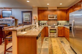 A modern kitchen with stainless steel appliances, granite countertops, and wooden cabinets.