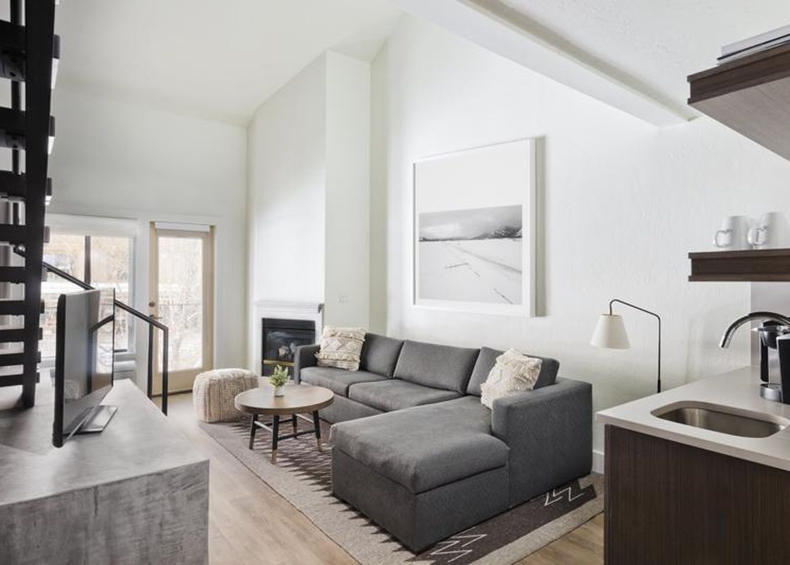Cozy living area in Gravity Haus JH Deluxe Loft with a gray sectional, a fireplace, and a kitchenette.