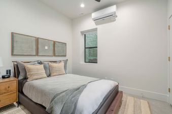 A bedroom with a bed, a nightstand, and a window with an exterior view.