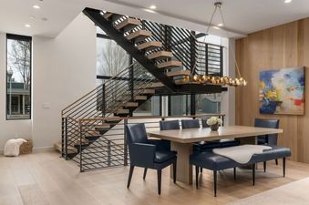 Modern dining table with blue chairs and a floating staircase in the background of Sky View Jackson Hole.