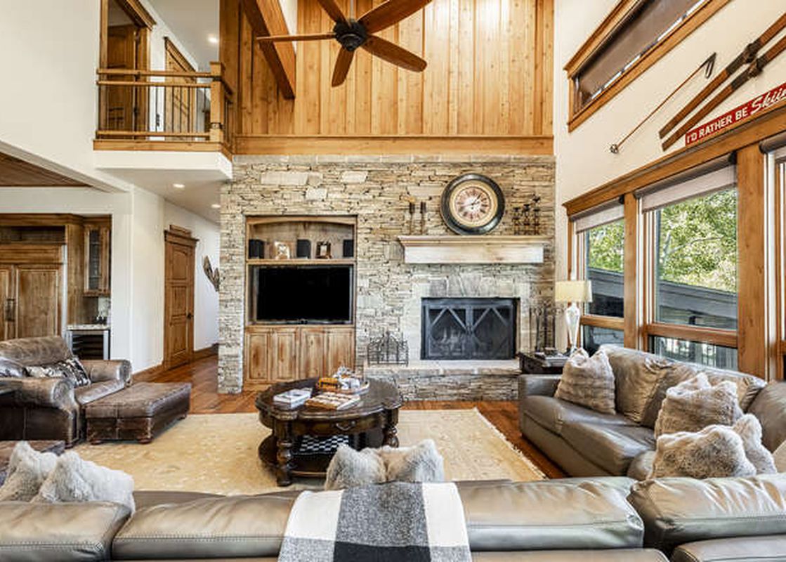 The living area of Deer Valley Lookout 26 features high ceilings, a stone fireplace, and comfortable sofas, creating a welcoming and spacious atmosphere.
