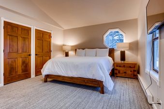A cozy bedroom at High Street Retreat featuring a king-size bed with white linens, wooden furniture, and a unique octagonal window.