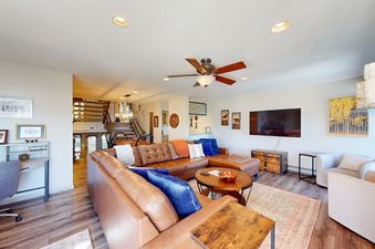 A spacious and inviting living room in La Casa 04 featuring a large brown leather sectional, flat-screen TV, and warm lighting.